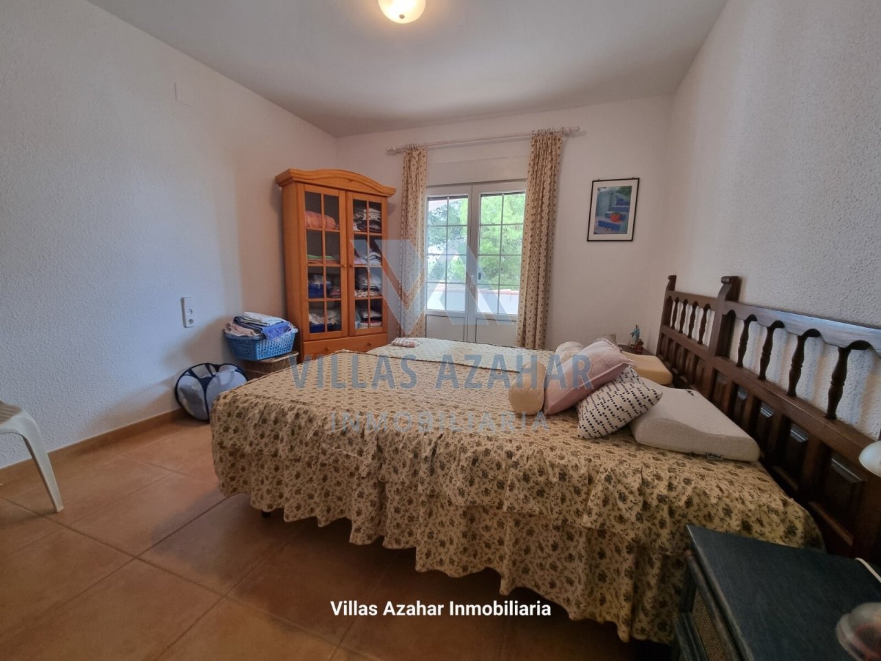 Dormitorio luminoso con vistas al jardín y un elegante vitrina de madera